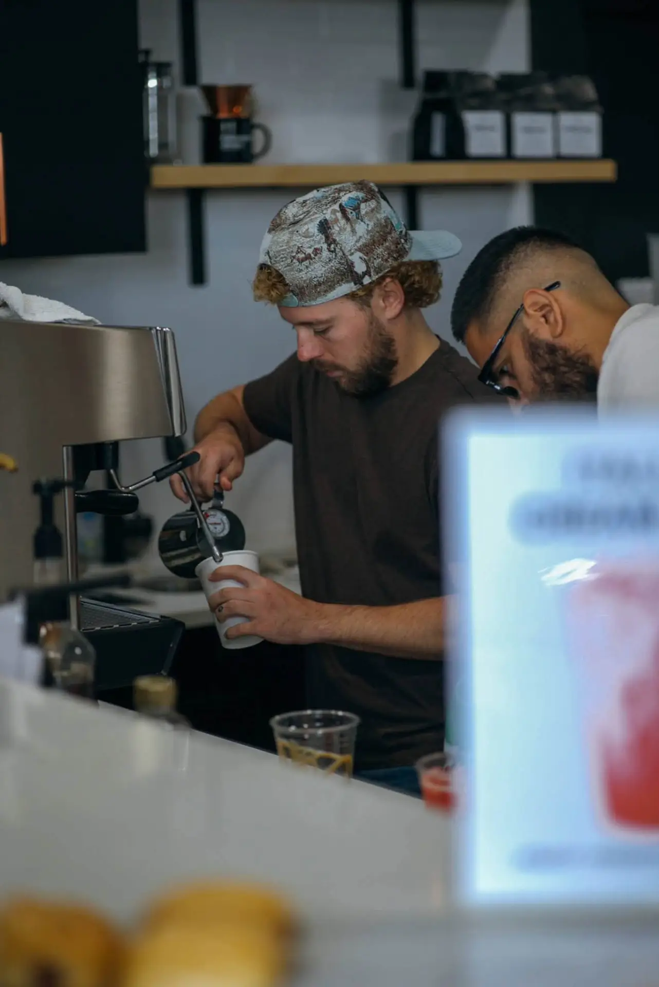 Baristas preparing coffee drinks behind a commercial coffee bar
