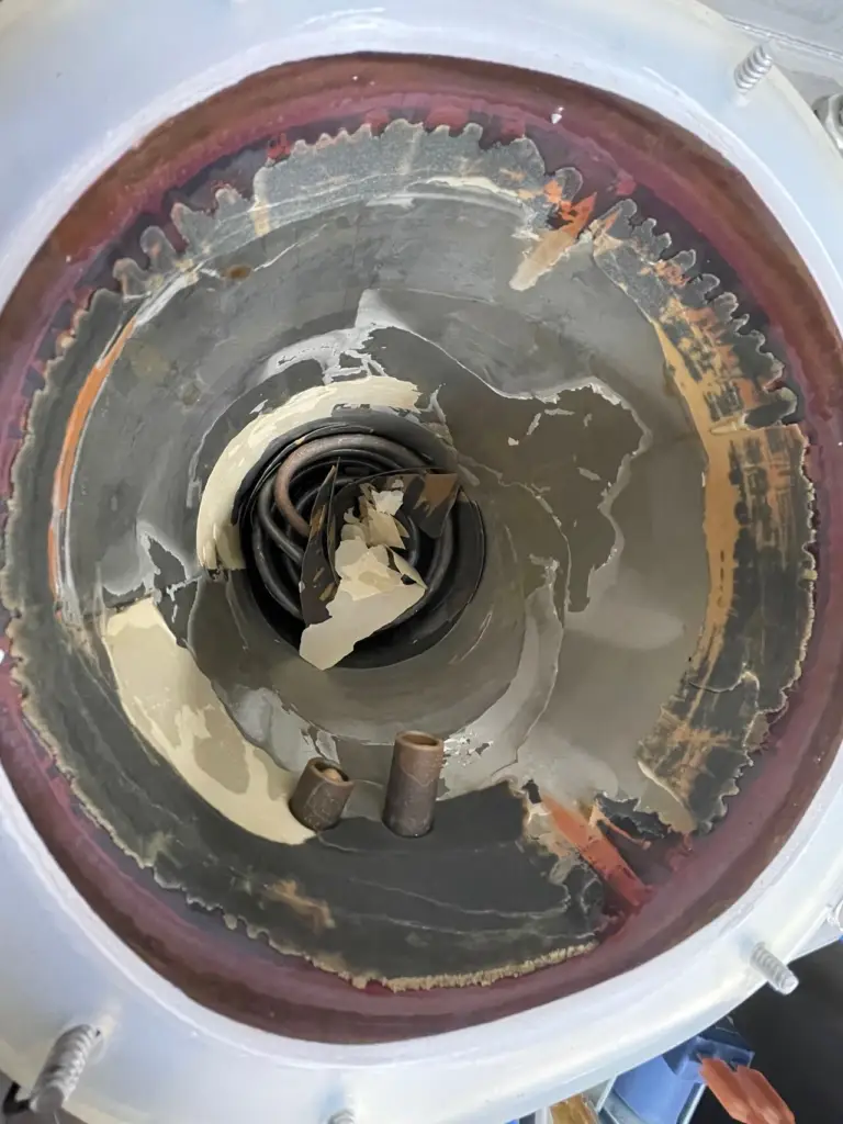 Lime scale flaking inside a hot water tank with the heating element underneath